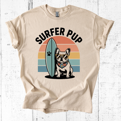 Beige t-shirt with 'Surfer Pup' design featuring a dog with sunglasses and a surfboard on a white wooden background