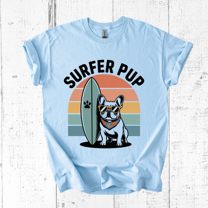 Light blue t-shirt with a graphic of a dog holding a surfboard and 'Surfer Pup' text on a white wooden background.