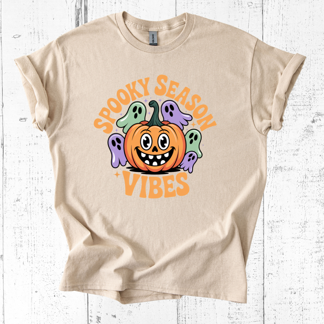 Beige t-shirt with Halloween design featuring a pumpkin and ghosts on a white wooden background