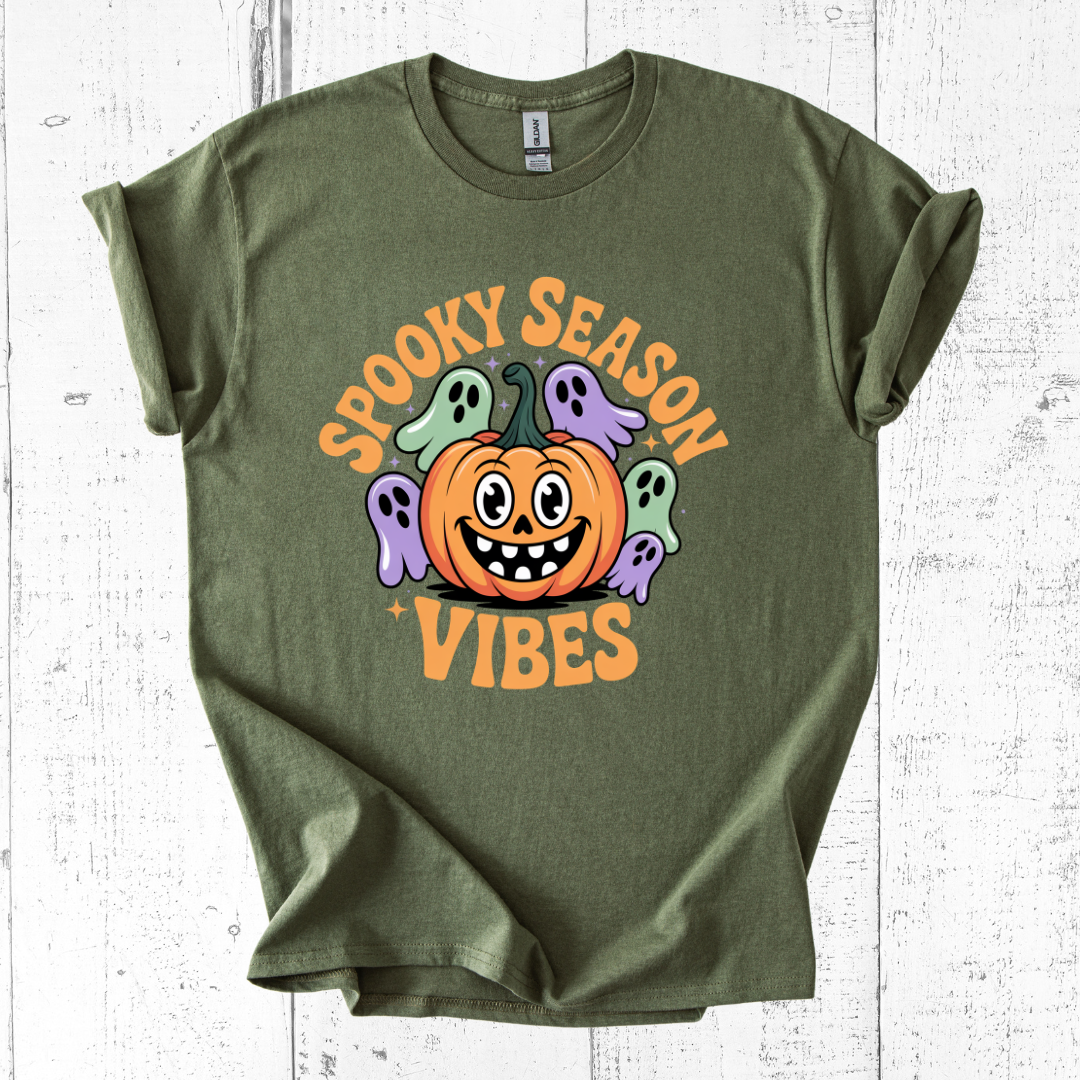 Green t-shirt with Halloween design featuring a pumpkin and ghosts on a white wooden background