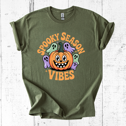 Green t-shirt with Halloween design featuring a pumpkin and ghosts on a white wooden background