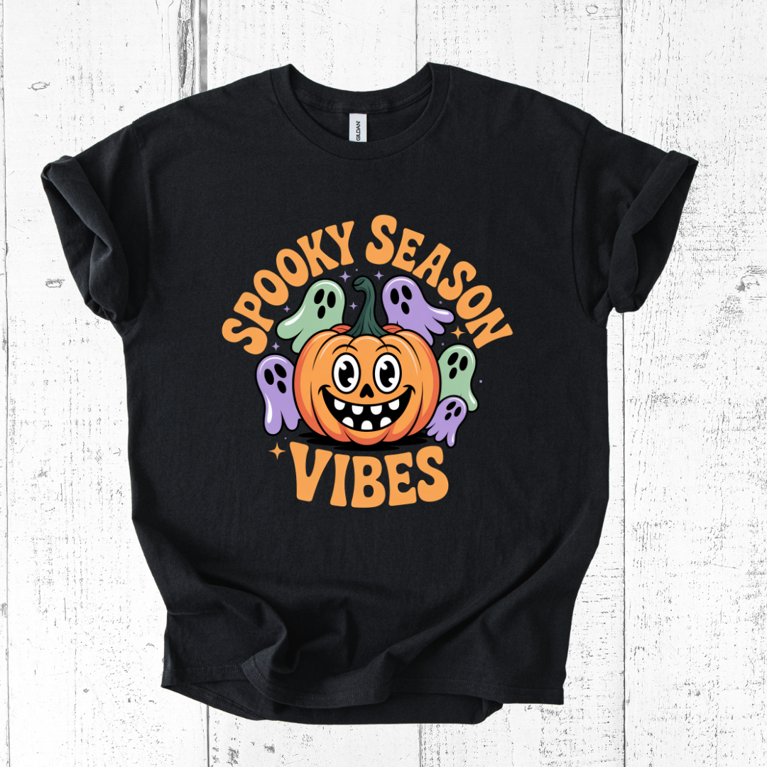 Black t-shirt with Halloween-themed design featuring a pumpkin and ghosts on a white wooden background.