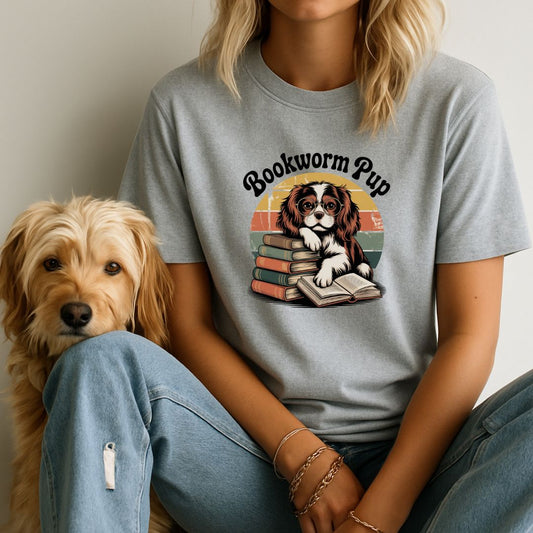 Person wearing a t-shirt with 'Bookworm Pup' design sitting next to a dog.