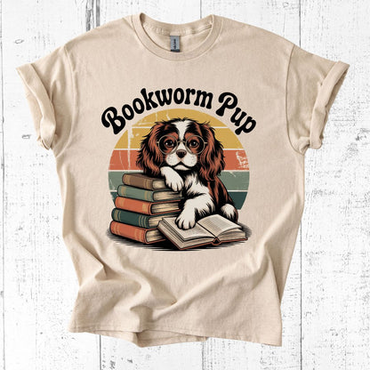 Beige t-shirt with a graphic of a dog and books and 'Bookworm Pup' text on a white wooden background