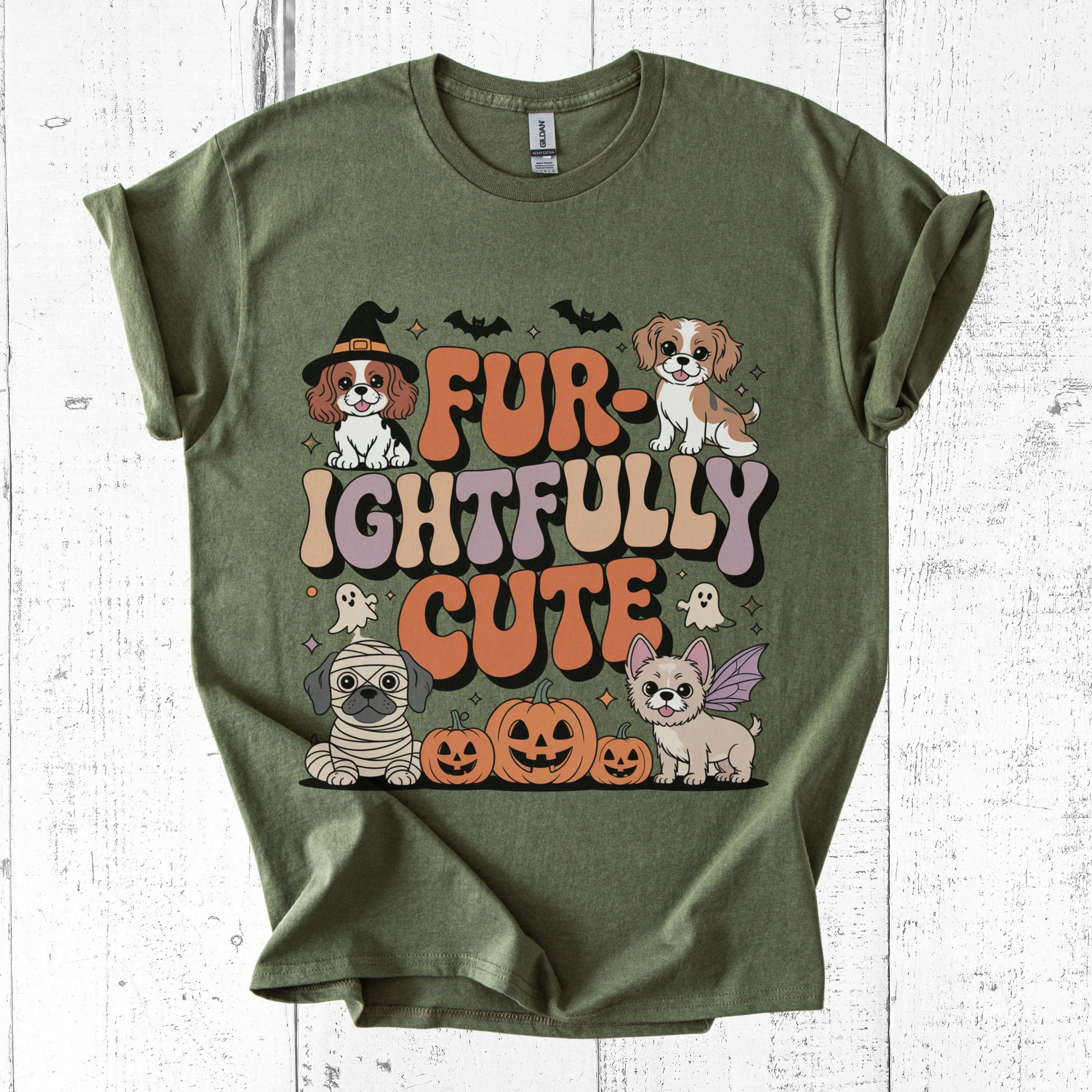 Green t-shirt with Halloween-themed design featuring dogs and text on a white wooden background
