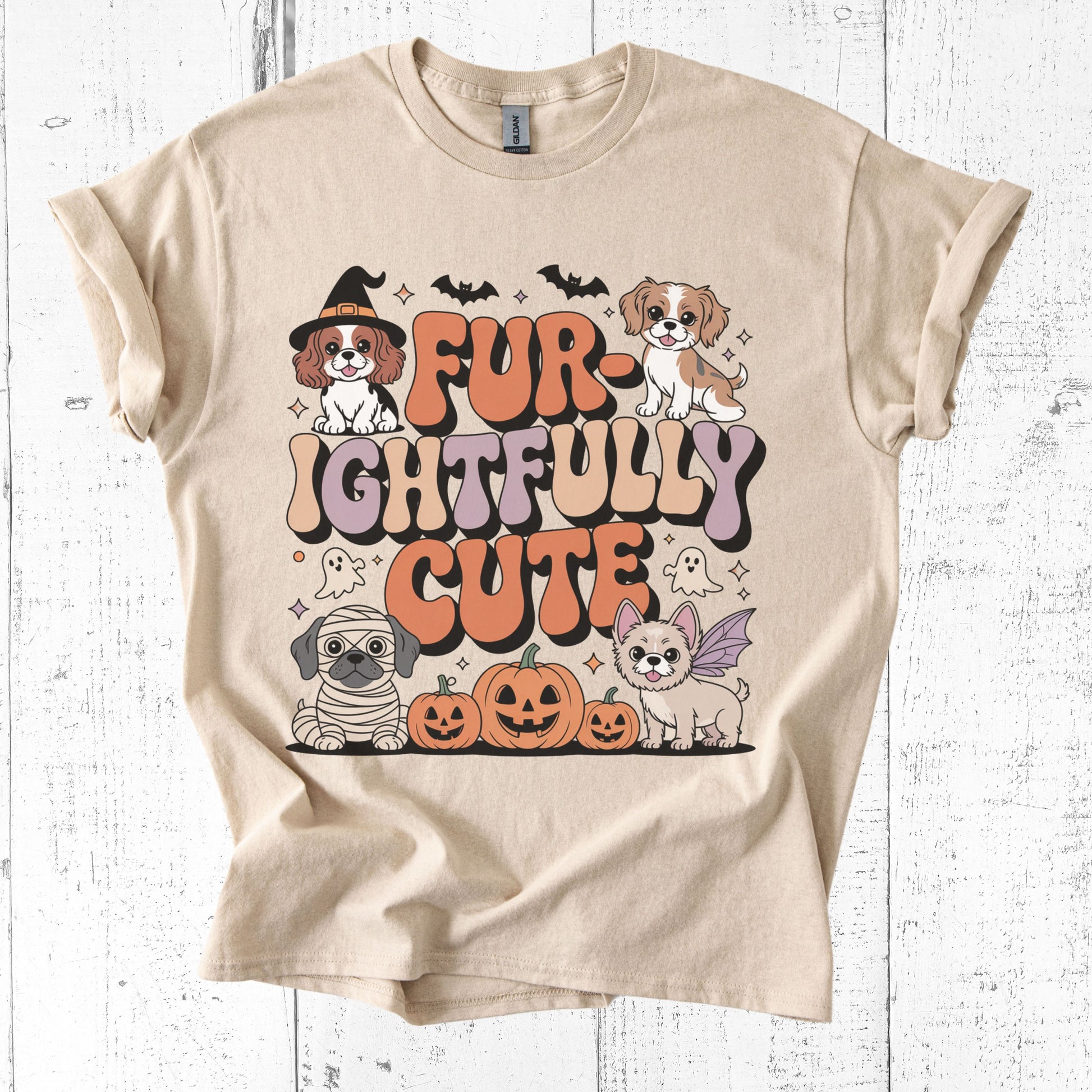 Beige t-shirt with Halloween-themed graphics and text on a white wooden background