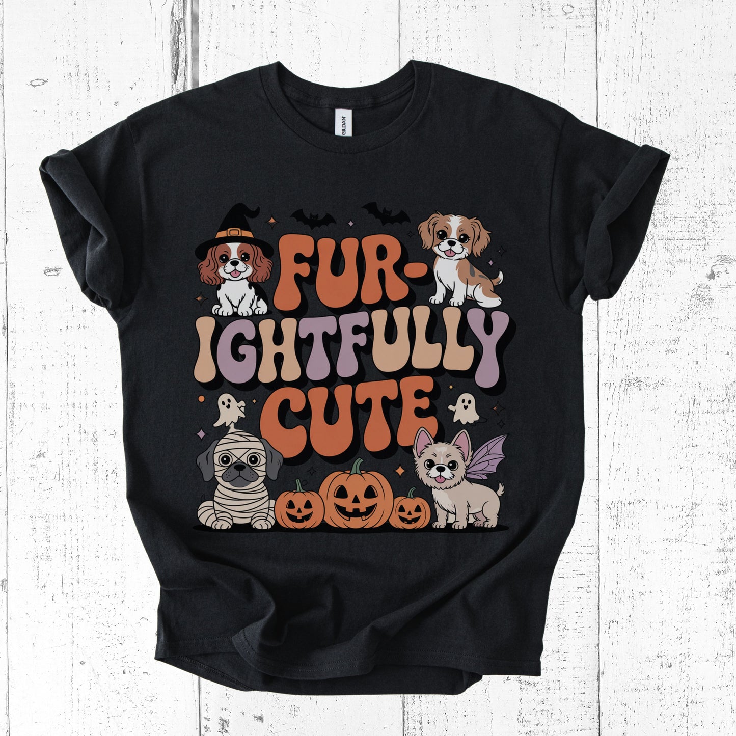 Black t-shirt with Halloween-themed graphic of dogs and text on a white wooden background