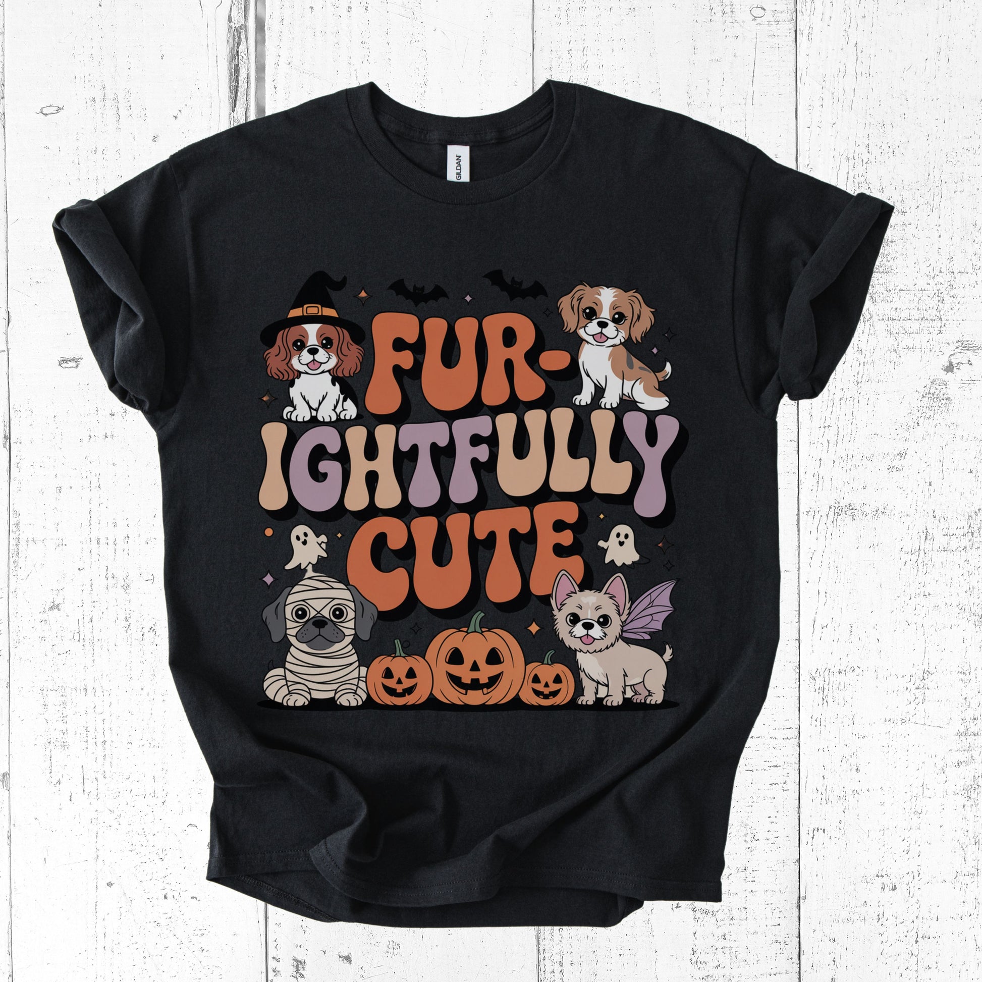 Black t-shirt with Halloween-themed graphic of dogs and text on a white wooden background