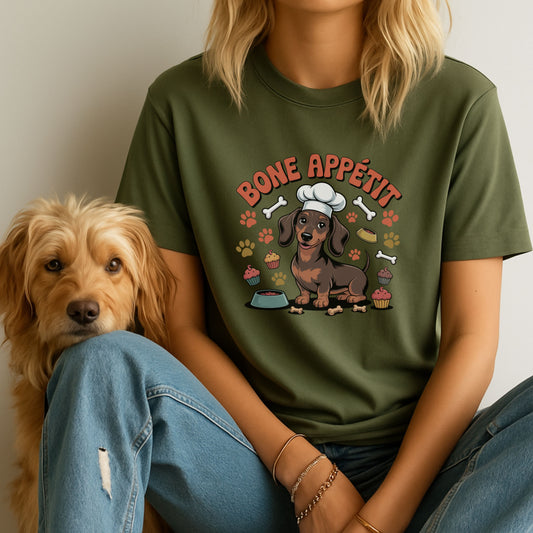 Person wearing a green t-shirt with a dachshund graphic and 'Bone Appetit' text, sitting next to a dog.