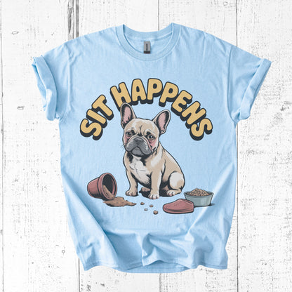 Light blue t-shirt with a cartoon dog and 'SIT HAPPENS' text on a wooden surface