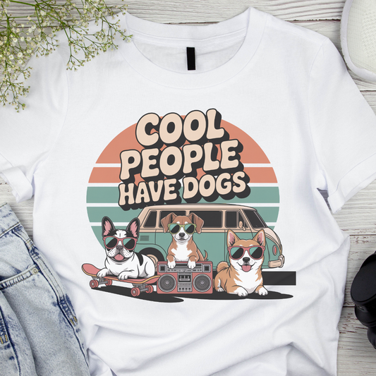 White t-shirt with 'Cool people have dogs' graphic design featuring dogs and a car.