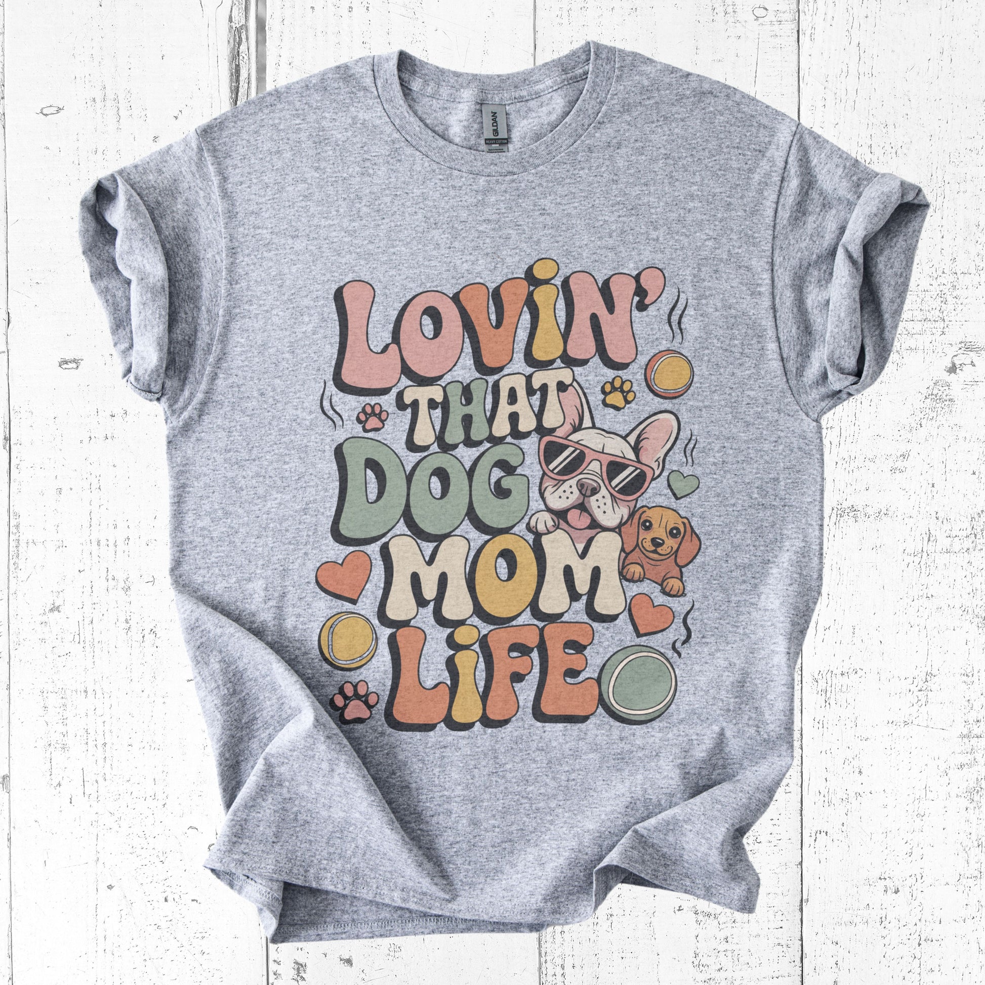Gray t-shirt with 'Lovin' That Dog Mom Life' graphic design on a white wooden background