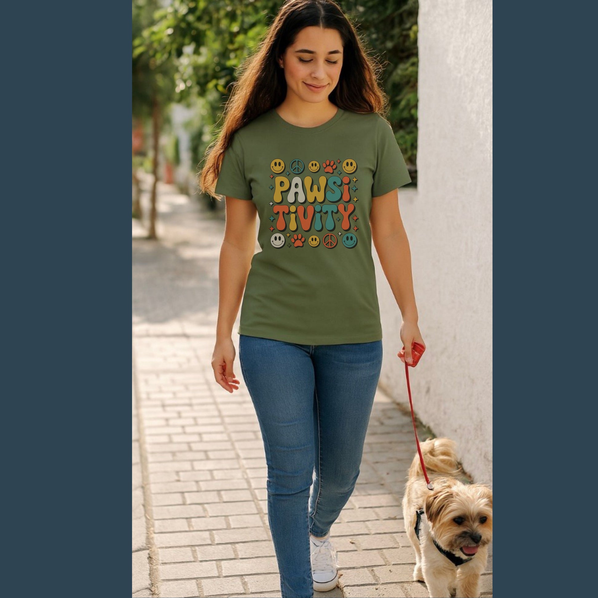 Woman walking a dog on a leash, wearing a green t-shirt with colorful text design.