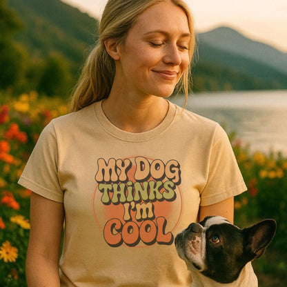 Woman wearing a t-shirt with 'My dog thinks I'm cool' text, standing in a scenic outdoor setting.