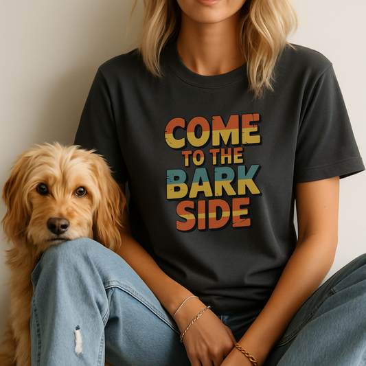 Person wearing a black t-shirt with 'COME TO THE BARK SIDE' text, sitting next to a dog.