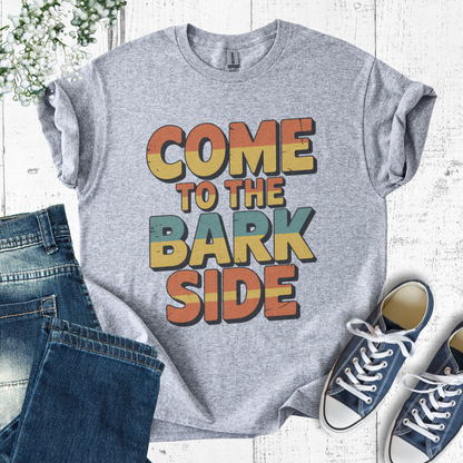 Gray t-shirt with 'Come to the Bark Side' text, paired with jeans and sneakers on a light wooden surface.