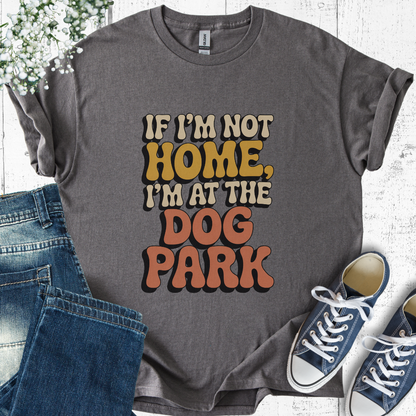 Gray t-shirt with 'If I'm not home, I'm at the dog park' text, paired with jeans and sneakers on a light wooden surface.