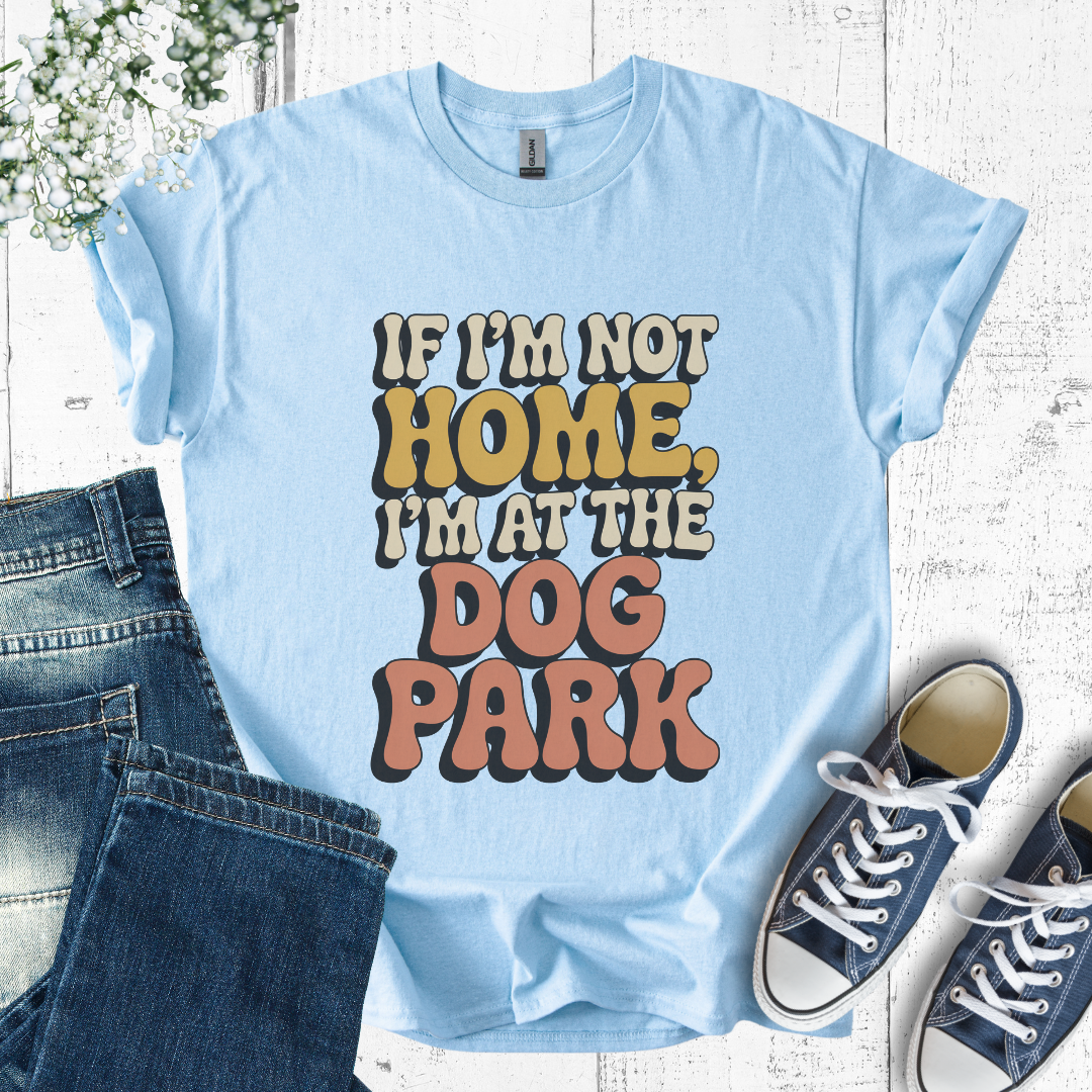 Light blue t-shirt with 'If I'm not home, I'm at the dog park' text, paired with jeans and sneakers on a wooden surface.