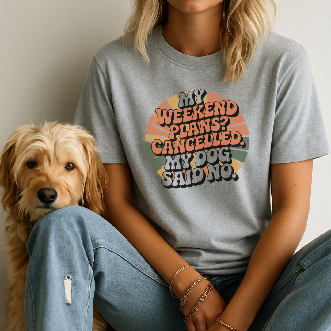 Person wearing a t-shirt with a humorous dog-related message sitting next to a dog.