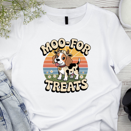 White t-shirt with a cow-themed graphic and text 'Moo-For Treats' on a wooden surface.