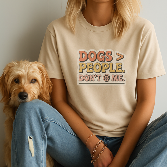 Person wearing a t-shirt with 'DOGS > PEOPLE. DON'T @ ME.' text sitting next to a dog.
