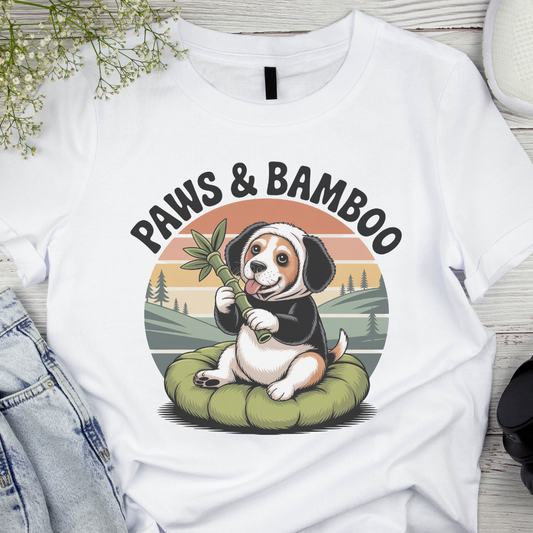 White t-shirt with a dog holding bamboo and 'Paws & Bamboo' text on a scenic background