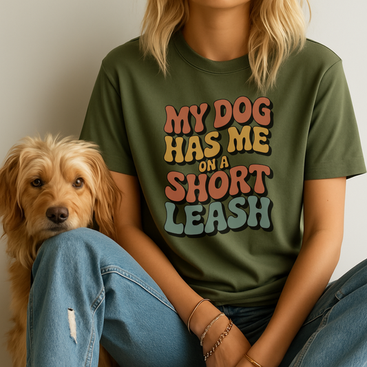 Person wearing a green t-shirt with a humorous dog quote, sitting next to a dog.