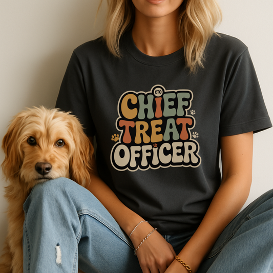 Person wearing a black t-shirt with 'Chief Treat Officer' text sitting next to a dog.