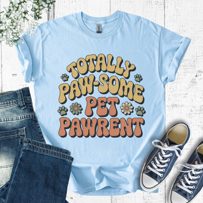Light blue t-shirt with 'Totally Paw-some Pet Pawrent' text, paired with jeans and sneakers on a wooden surface.