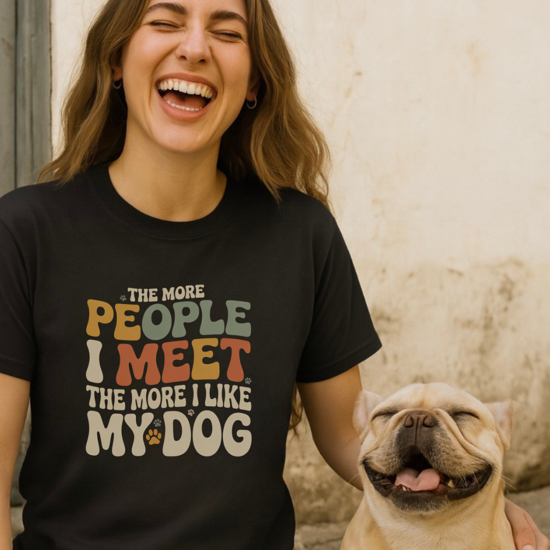 Person wearing a black t-shirt with a colorful text design, holding a dog.