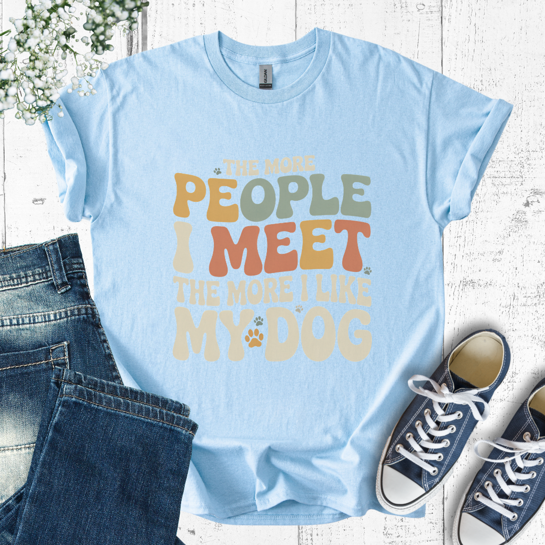 Light blue t-shirt with colorful text, paired with jeans and sneakers on a wooden surface.