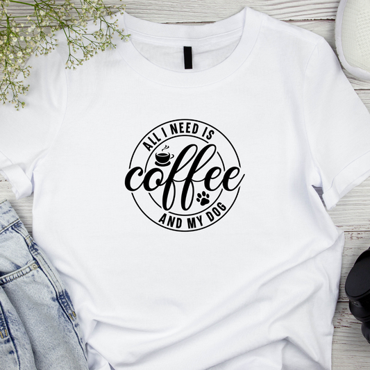 White t-shirt with 'All I Need is Coffee and My Dog' text on a wooden surface.