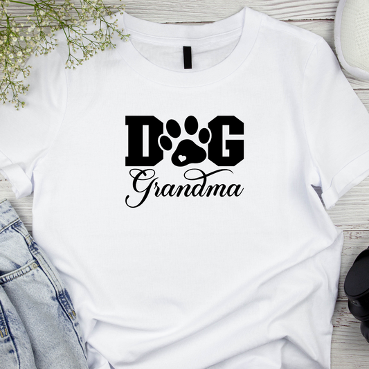 White t-shirt with 'Dog Grandma' text and paw print design on a wooden surface.