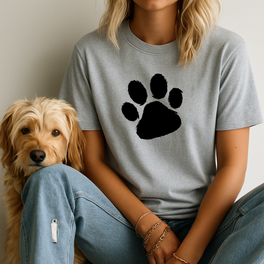 Person wearing a gray t-shirt with a black paw print design, sitting next to a dog.