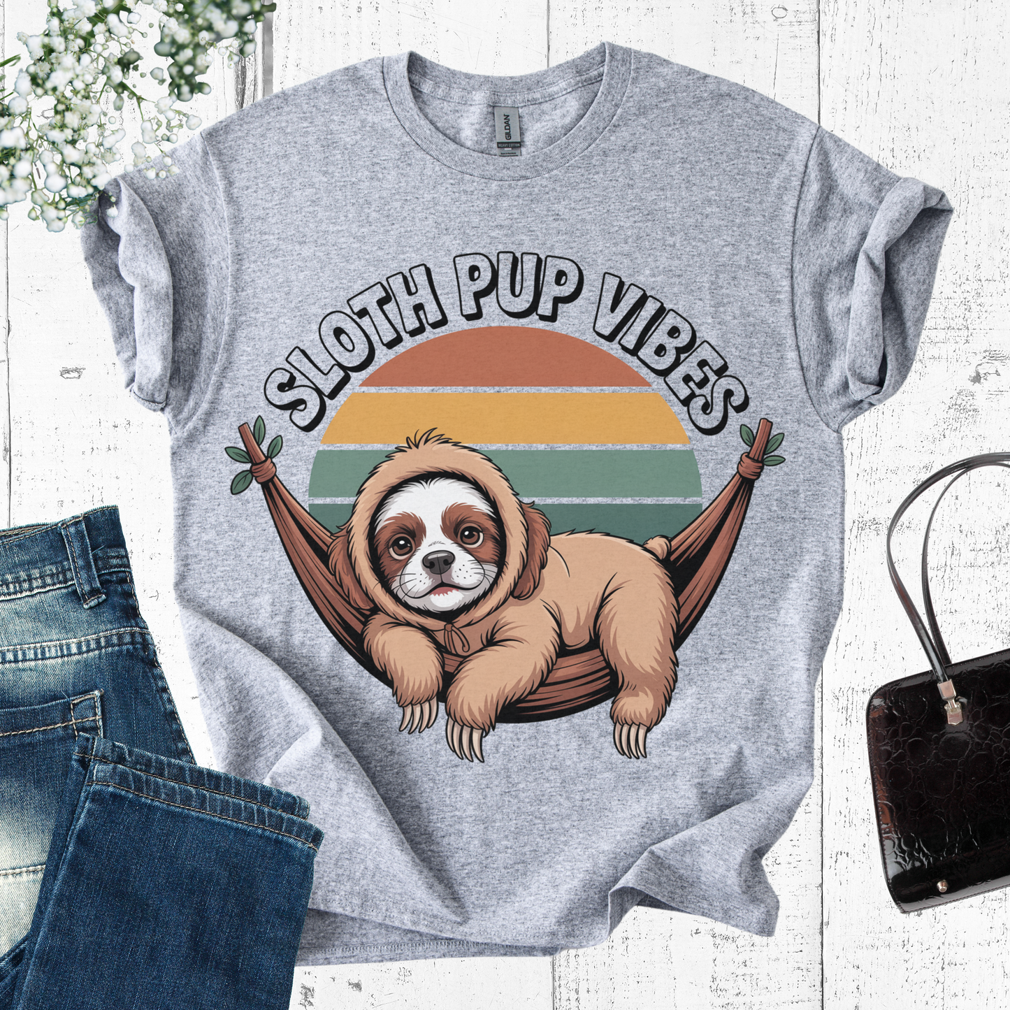 Gray t-shirt with sloth and dog hybrid graphic and 'Sloth Pup Vibes' text on a wooden surface.