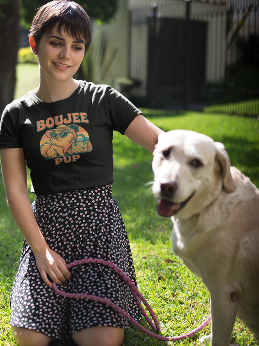 Woman in a black t-shirt with a graphic design, standing outdoors with a white dog on a leash.