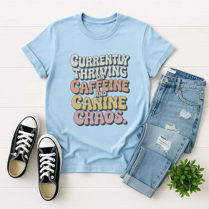 Light Blue Gildan 6400 unisex t-shirt with retro dog graphic and ‘Currently Thriving On Caffeine And Canine Chaos’ text, perfect for dog lovers.