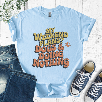 Light blue t-shirt with 'My weekend plans? Dogs & doing nothing' text, paired with jeans and sneakers on a wooden surface.